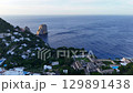 Stunning coastal view of rocky formations and lush greenery overlooking serene blue waters at dawn 129891438