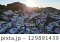 Sunrise over a tranquil hillside village with charming white buildings and lush greenery nestled in the hills 129891439