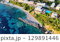 Serenity unfolds on a tranquil coastal stretch with vibrant waters and a lush hillside at dusk 129891446