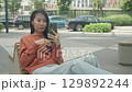 Shocked Woman Reacts To Bad News During Video Call On City Bench 129892244