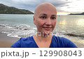 bald head woman making selfie on the beach on sunset 129908043