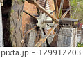 Rotating water mill. Old wooden water mill. Mill wheel rotating under stream of water at village 129912203