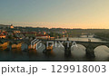 Experience the serene beauty of Prague in the early morning, showcasing the stunning panorama of Prague Castle and Charles Bridge bathed in soft sunrise light over the Vltava River. 129918003
