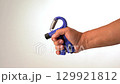 Hand using blue hand grip strengthener for exercise, rehabilitation, and building hand strength, holding blue hand strengthener adjustable grip exerciser for muscle training, physical therapy tool 129921812