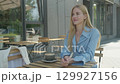 Smiling Blonde Woman Gesturing During Conversation At Outdoor Cafe Table 129927156