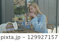 Blonde Woman Daydreaming At Outdoor Cafe Table With Coffee In Blue Outfit 129927157