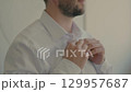 Man buttoning shirt close up. 129957687