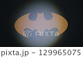 A bright bat symbol shines on a dark surface, captivating attention during a nighttime gathering. 129965075