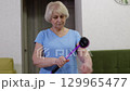 Elderly woman performing self massage with roller massager 129965477