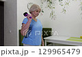 Elderly woman performing arm exercises with massage tool at home 129965479