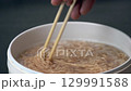 Instant noodle chopsticks boiling water hot soup quick meal Asian cuisine comfort food, holding chopsticks stirring instant noodles hot water, steaming simple delicious easy cooking savory aroma 129991588