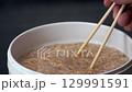 Chopsticks lift steaming instant noodles from boiling water white pot, creating appetizing scene as hot steam rises, cooking quick and easy Asian meal with soft texture, comfort food, and delicious 129991591