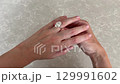 A landscape video of female hands holding and presenting an oval diamond engagement ring set on a platinum band against a marble surface, highlighting bridal jewelry, elegance and luxury. 129991602
