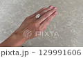 A landscape video showing a womans hand wearing a large oval diamond engagement ring on a platinum band resting on light marble. 129991606