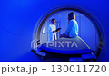 Handsome Caucasian Doctor talking to patient before MRI. Patient talking about symptoms before tomography. Patient sitting at CT scanner doctor adjusting MRI capsule. Conducting advanced imaging 130011720