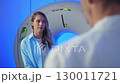 Doctor talking to patient before MRI. Portrait patient talking about symptoms before tomography. Portrait Patient sitting at CT scanner doctor adjusting MRI capsule. Conducting advanced imaging 130011721