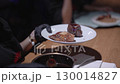 Chef pouring sauce over meat and potatoes on plate. 130014827