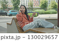 Relaxed Woman Talking On Phone While Lounging On Modern Urban Bench 130029657
