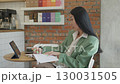 Asian Businesswoman Taking Notes During Video Call At Stylish Cafe Workspace 130031505
