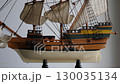 4K video of wooden model of three-masted sailing vessel on a stand rotates around closeup view 130035134