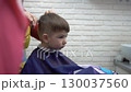 toddler smiling in barber chair while getting a haircut 130037560