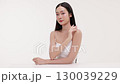 Skincare commercial video featuring a young Asian woman applying natural cosmetic cream in a soft, minimal studio setting. Ideal for promoting beauty, self-care, and organic skincare products. 130039229