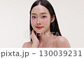 Skincare commercial video featuring a young Asian woman applying natural cosmetic cream in a soft, minimal studio setting. Ideal for promoting beauty, self-care, and organic skincare products. 130039231
