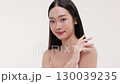 Skincare commercial video featuring a young Asian woman applying natural cosmetic cream in a soft, minimal studio setting. Ideal for promoting beauty, self-care, and organic skincare products. 130039235
