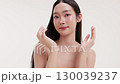 Skincare commercial video featuring a young Asian woman applying natural cosmetic cream in a soft, minimal studio setting. Ideal for promoting beauty, self-care, and organic skincare products. 130039237