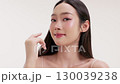 Skincare commercial video featuring a young Asian woman applying natural cosmetic cream in a soft, minimal studio setting. Ideal for promoting beauty, self-care, and organic skincare products. 130039238