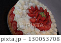 Delightful fraisier cake topped with fresh strawberries and whipped cream is served at a gathering 130053708