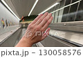 A platinum engagement ring, wedding band sparkle on a female hand while riding a subway escalator with bright lights and sleek architecture in view. 130058576