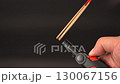 Lighting incense stick with lighter flame close up hand holding lighter igniting incense smoke rising black background spiritual ritual calm atmosphere meditation relaxation traditional practice focus 130067156