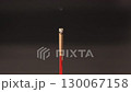 Burning incense stick with gentle smoke rising in dark background, creating calm and peaceful atmosphere for meditation, relaxation, spiritual calming, and focus 130067158