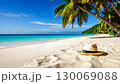 Straw hat lies on idyllic tropical beach under palm trees. 130069088