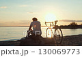 Cyclist resting at sunset on beach 130069773