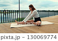 Young woman performing leg stretching exercise outdoors 130069774