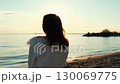 Woman wearing white dress watching golden sunset at beach 130069775