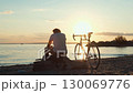 Cyclist resting at sunset on beach 130069776