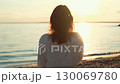 Woman watching golden sunset over calm ocean 130069780