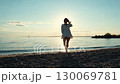 Woman walking on beach at sunset, feeling the breeze 130069781