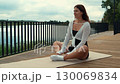 Woman practicing yoga poses near a lake 130069834