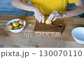 Hands peeling a potato over a wooden cutting board, with a bowl of potatoes an empty bowl nearby, ready for preparation fullhd video food 130070110