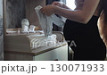 A pregnant woman carefully folds and arranges baby clothes and accessories on a changing table in preparation for the arrival of her newborn. Pregnant woman awaiting the birth of her child. 130071933