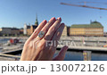 A landscape video of an oval diamond engagement ring or wedding band worn on a hand with city architecture and water views under bright summer light. 130072126