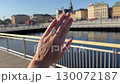 A landscape video close up of an oval diamond engagement ring or wedding band sparkling on a hand with Scandinavia buildings and blue sky in the background. 130072187