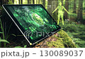 Futuristic tablet showing rotating green earth and human body in forest setting 130089037