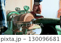 Closeup of carpenter sanding wooden product using sandpaper on a lathe. 130096681