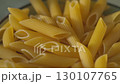 Uncooked Penne Pasta in Bowl on Kitchen Table Camera Tilt Down 130107765