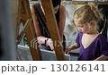 Child painting with an grandmother in a cozy art studio. Candid indoor moment of creativity and learning. Artistic lifestyle scene with real people and natural light. 130126141